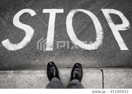 Feet of a man and stop road marking label Feet of a man and stop road marking label 35100932