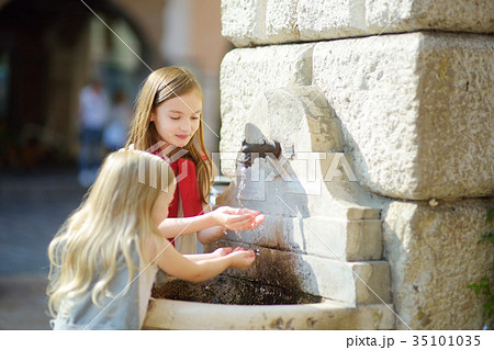 Two cute little girls playing with a drinking water fountain  35101035