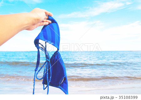 Woman hand holding bikini with sea and blue sky Woman hand holding bikini with sea and blue sky 35108399