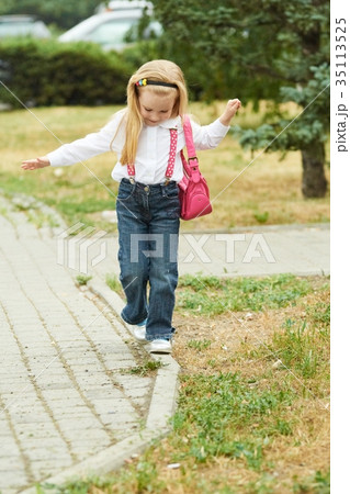 Young girl walk on curb. Jeans, ping bag 35113525