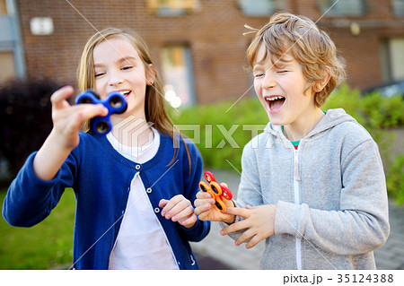 Two funny friends playing with fidget spinners on the playground 35124388