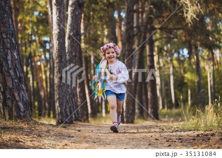 A little girl in a wreath with ribbons is running A little girl in a wreath with ribbons is running 35131084