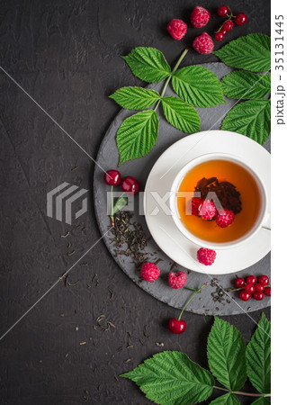 cup of tea and ripe raspberry, cherry, currant  35131445