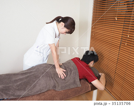 腰のマッサージをする女性マッサージ師の写真素材