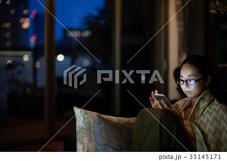 女性 夜 スマホの写真素材
