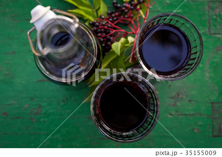 Glasses of fresh elderberry syrup and elderberries 35155009