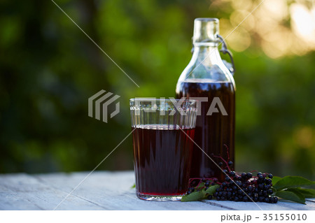 Glass of fresh elderberry syrup and elderberries 35155010