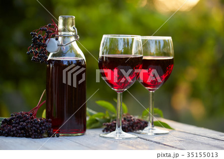 Glasses of elderberry wine and elderberries 35155013
