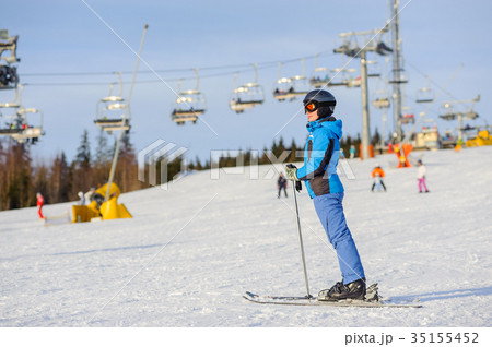 Woman skier skiing downhill at ski resort against ski-lift Woman skier skiing downhill at ski resort against ski-lift 35155452