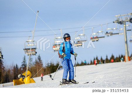 Woman skier skiing downhill at ski resort against ski-lift Woman skier skiing downhill at ski resort against ski-lift 35155453