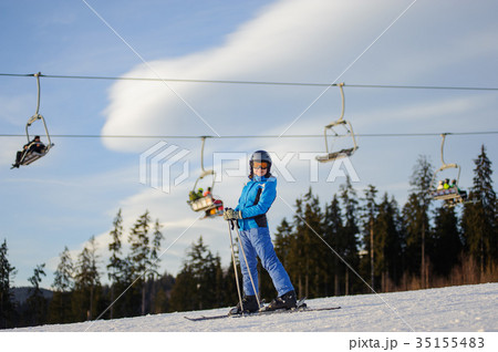 Female skier against ski-lift and forest on a sunny day Female skier against ski-lift and forest on a sunny day 35155483