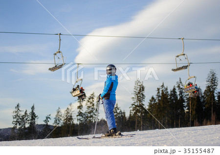 Female skier against ski-lift and forest on a sunny day 35155487
