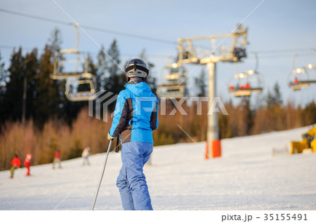 Female skier against ski-lift and forest on a sunny day 35155491