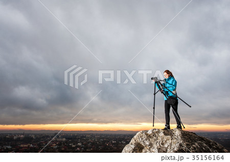 Female photographer with camera on tripod on the big rock 35156164