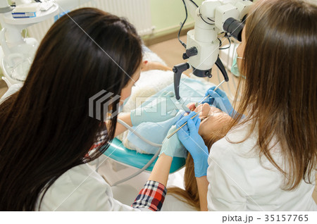 Female dentist treating caries using microscope at the dentist office 35157765