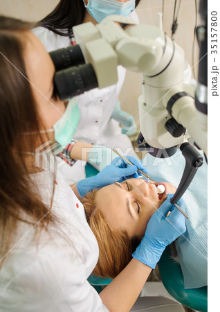 Female dentist treating caries using microscope at the dentist office Female dentist treating caries using microscope at the dentist office 35157800