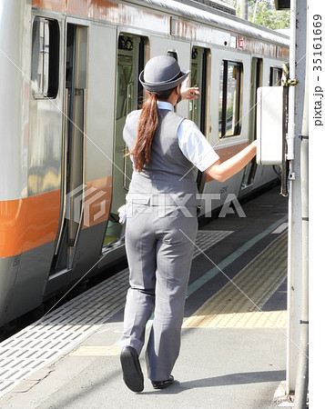 午後の陽光に照らされる女性車掌さんの写真素材