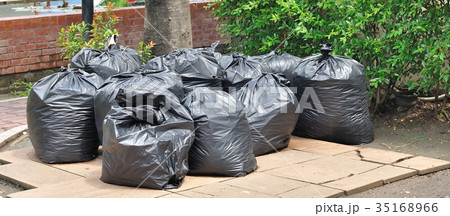 Pile of black garbage plastic bags on ground 35168966