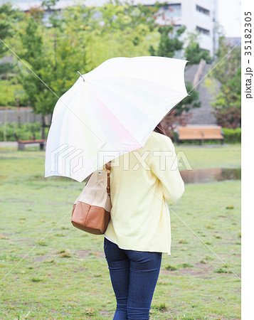 公園で傘をさす女性の後ろ姿の写真素材