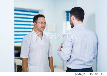 Doctor talking to a patient in a hallway Doctor talking to a patient in a hallway 35184619