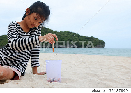 Volunteer girl collecting cigarette butts on beach Volunteer girl collecting cigarette butts on beach 35187899