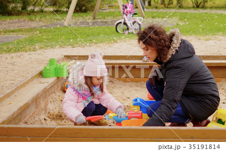 Mother playing with her daughter in a sandbox Mother playing with her daughter in a sandbox 35191814