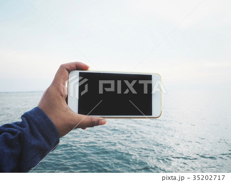 Smart phone on hand with beach 35202717