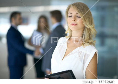 Blonde woman with touchpad computer looking at 35210801