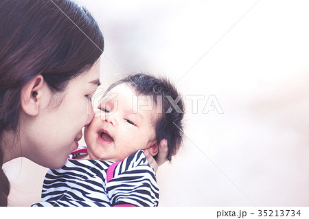 mother hugging and kissing her newborn baby girl mother hugging and kissing her newborn baby girl 35213734