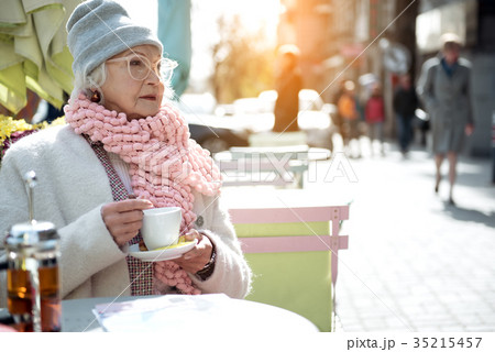 Pensive mature lady sitting outside with mug of 35215457