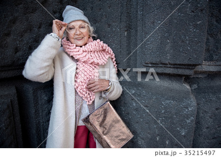 Cheerful mature lady posing near concrete wall of Cheerful mature lady posing near concrete wall of 35215497