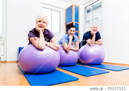 Physio showing senior couple how to use gym ball 35217121