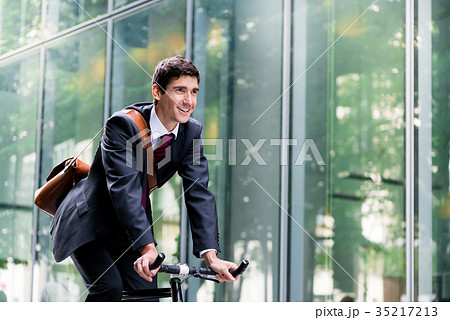 Cheerful young employee riding an utility bicycle Cheerful young employee riding an utility bicycle 35217213