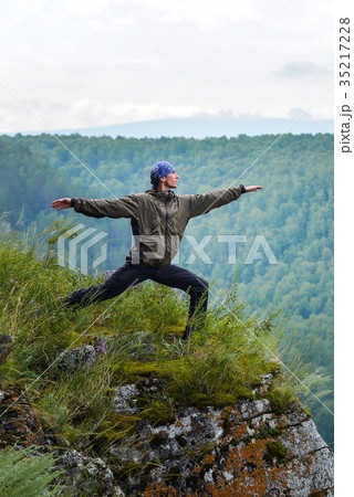 Man traveller practicing yoga warrior pose on the 35217228