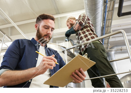 men with clipboard at brewery or beer plant kettle men with clipboard at brewery or beer plant kettle 35228253