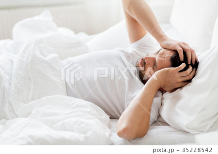 man in bed at home suffering from headache man in bed at home suffering from headache 35228542