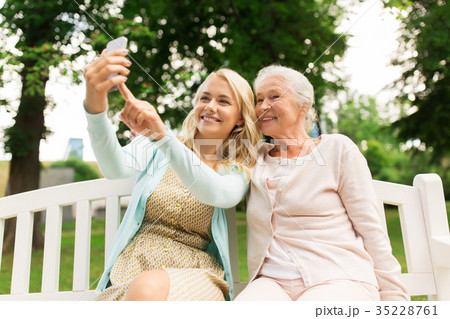 daughter and senior mother taking selfie at park 35228761