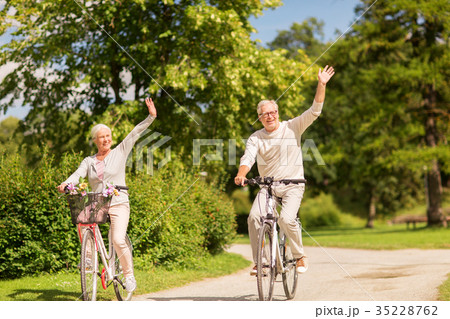 happy senior couple riding bicycles at park 35228762