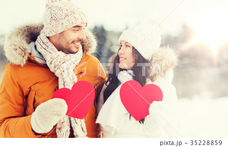 happy couple with red hearts over winter landscape 35228859