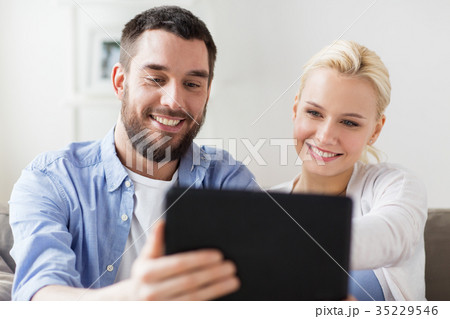 smiling happy couple with tablet pc at home smiling happy couple with tablet pc at home 35229546
