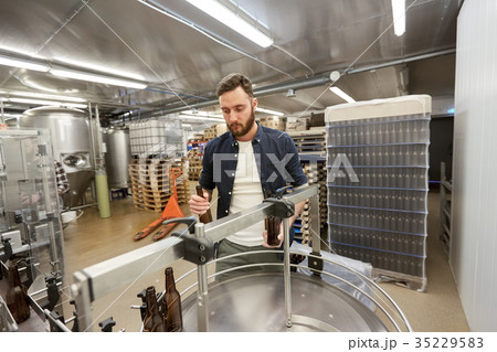 men with bottles on conveyor at craft beer brewery men with bottles on conveyor at craft beer brewery 35229583