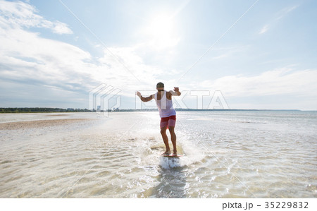 young man riding on skimboard on summer beach 35229832