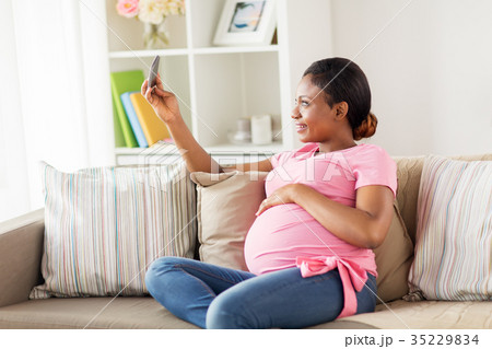 pregnant woman taking smartphone selfie at home pregnant woman taking smartphone selfie at home 35229834