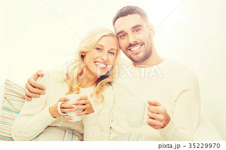 happy couple with cups drinking tea at home 35229970