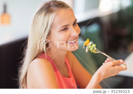 happy young woman eating at restaurant 35230323