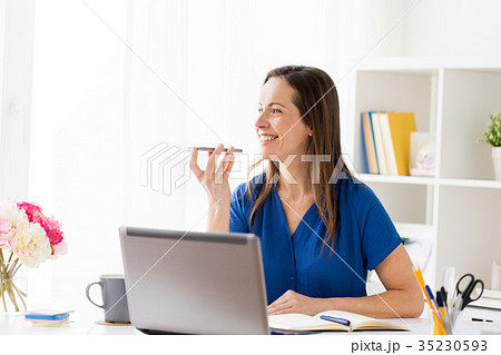 woman using voice recorder on smartphone at office 35230593