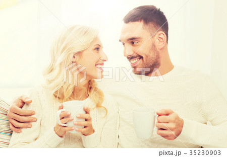 happy couple with cups drinking tea at home happy couple with cups drinking tea at home 35230903