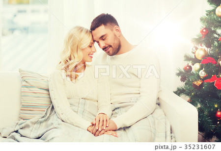 happy couple covered with plaid on sofa at home happy couple covered with plaid on sofa at home 35231607