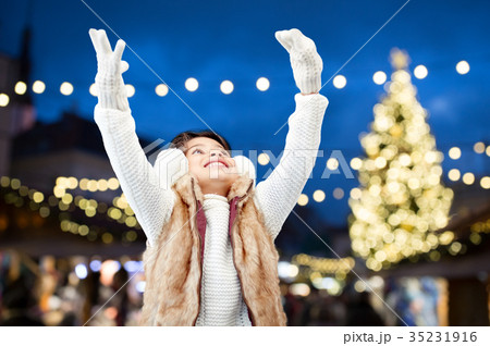 happy girl wearing earmuffs over christmas lights happy girl wearing earmuffs over christmas lights 35231916