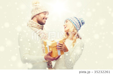 smiling couple in winter clothes with gift box smiling couple in winter clothes with gift box 35232261